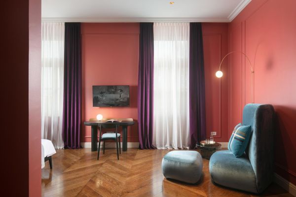 Radiant elegance in Deluxe double room 'von Trapp' at Almayer Art & Heritage Hotel's annexe building: bright interior, stylish table, cozy sofa.