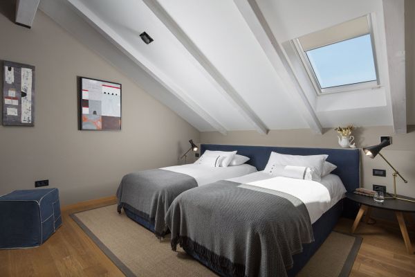Inviting and cosy mezzanine bedroom in Deluxe mezzanine double room 'Siroco' at Almayer Art & Heritage Hotel, featuring a king-sized bed separated into twin beds