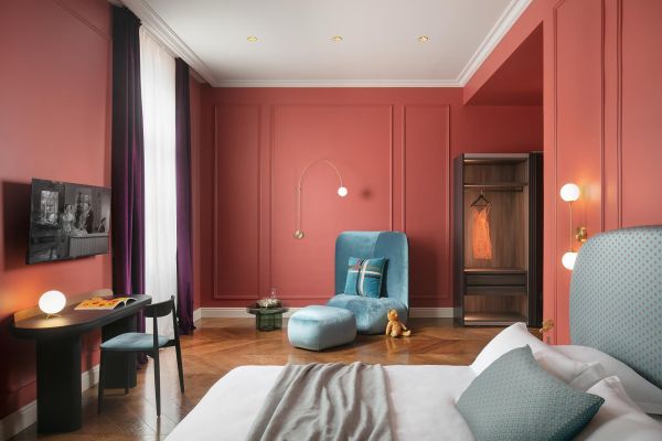 Refined elegance within the Deluxe double room 'von Trapp' at Almayer Art & Heritage Hotel's annexe building, featuring a luxurious king-sized bed, a stylish table, and a comfortable sofa